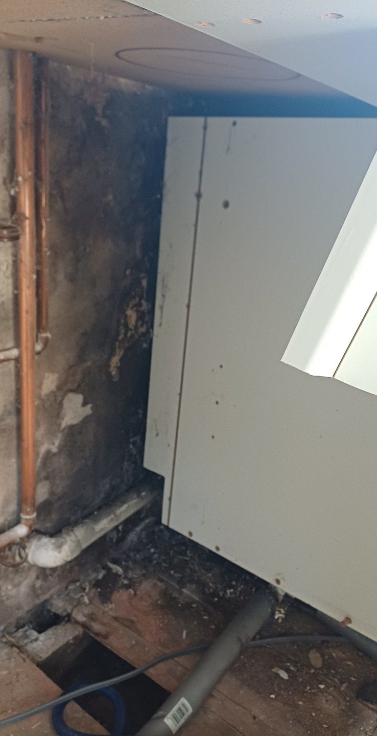 The same wall taken back to sound brick with the failed pipework exposed.