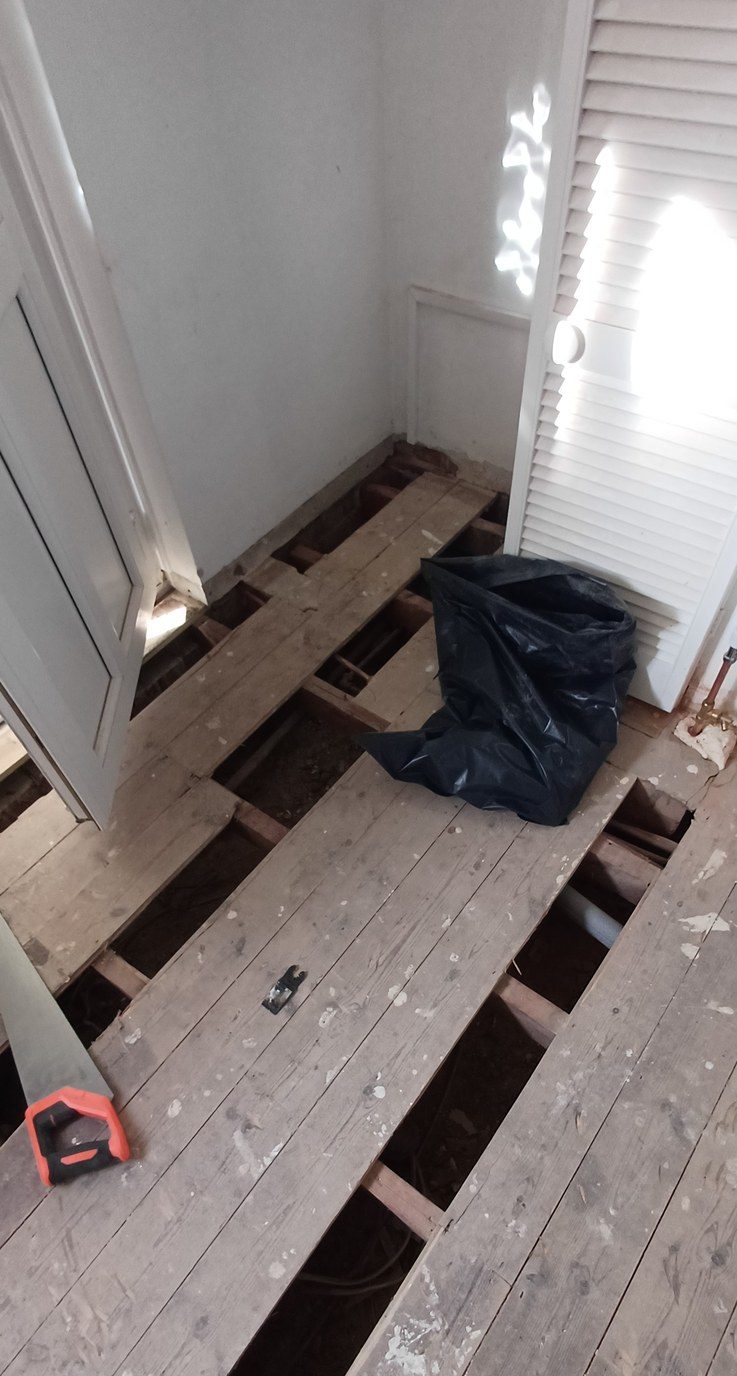 Boards up and joists open — the only cheap moment to check pipework and insulate.