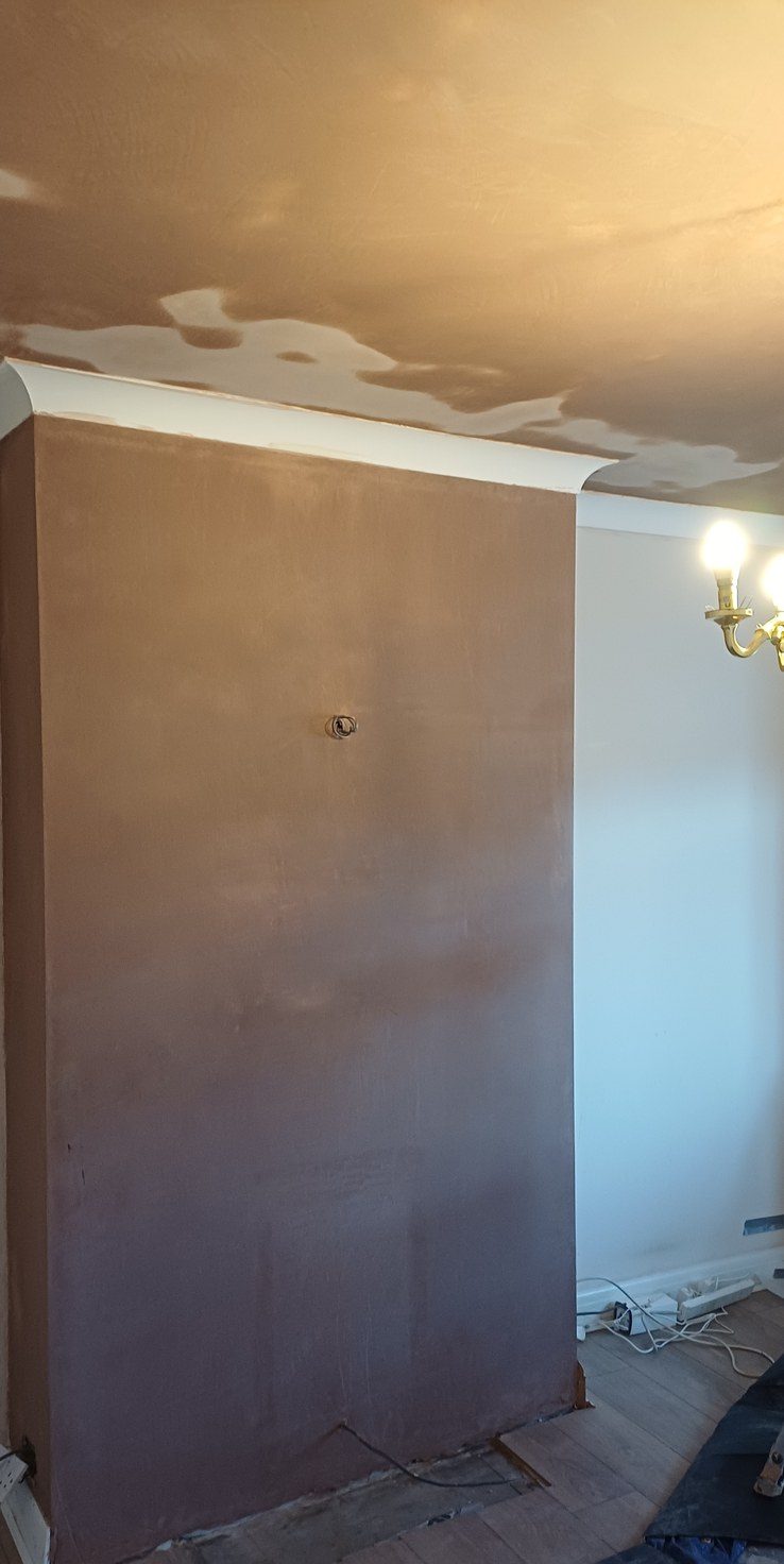 A chimney breast stripped, floated and skimmed, drying from dark to pink before it can be painted.