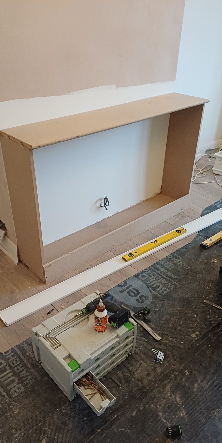 An alcove unit built on site in MDF, levelled with a spirit level laid across the shelf.
