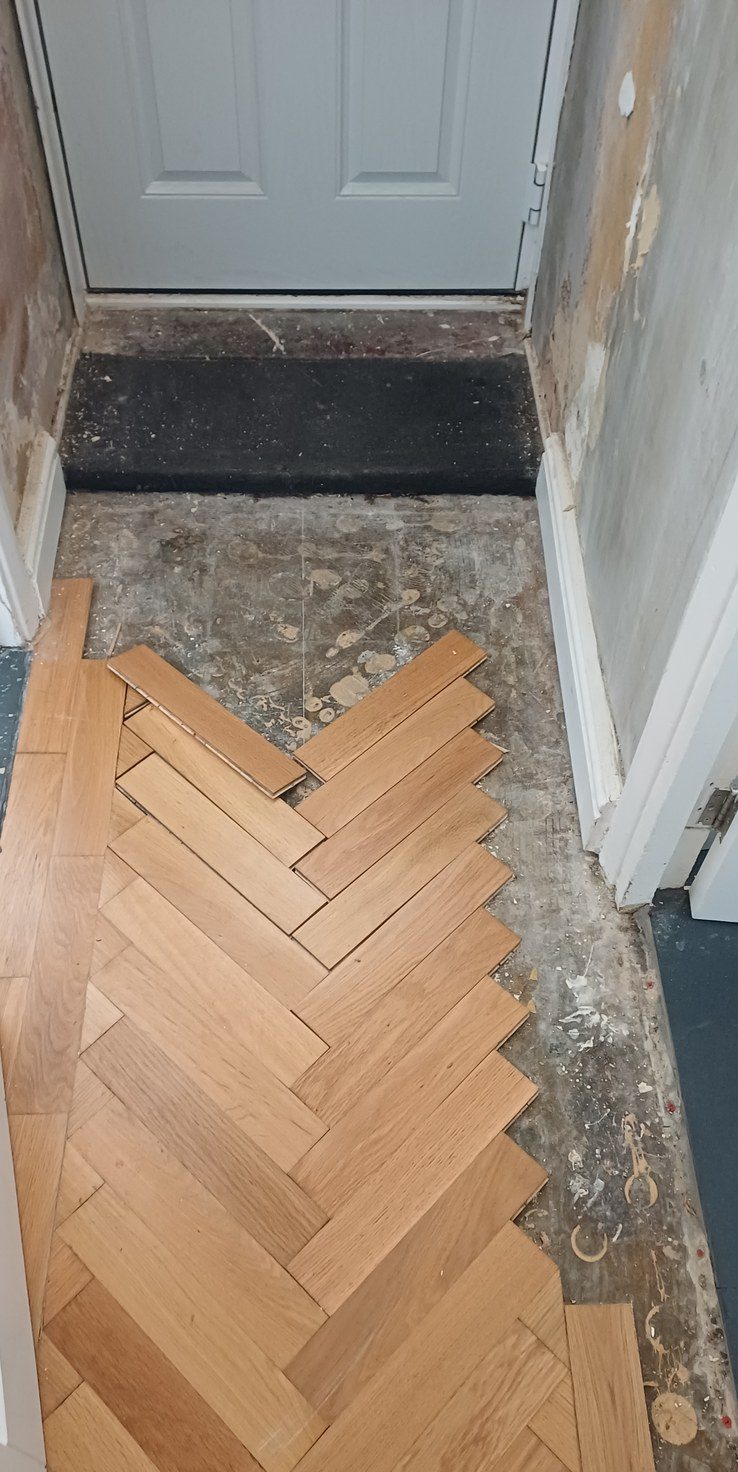 Herringbone part-laid, set out from the centre line so the cuts finish under the skirting.